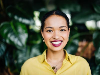 Portrait Of beautiful woman Smiling In Front Of Large, Leafy Plants