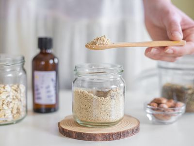 DIY oatmeal almond scrub in glass jar with wooden spoon