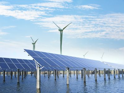 solar panels and wind turbines under blue sky on summer landscape