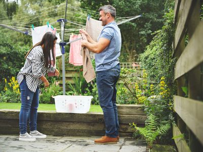 A couple saves energy by hanging up their laundry to air dry in the garden outside.