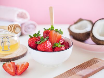 bowl of strawberries, split fresh coconut, and honey for diy hair mask