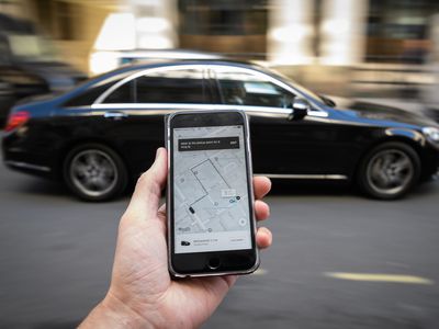 A hand holding a phone with an Uber app open.