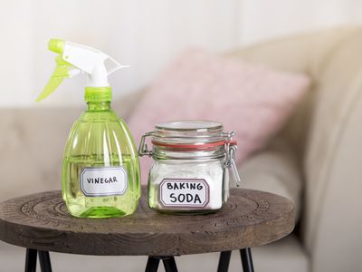 Using baking soda Sodium bicarbonate and white vinegar for home cleaning. White vinegar in spray bottle and baking soda in glass jar.