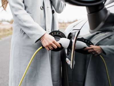 view of woman's hand plugging in charging lead to her electric car