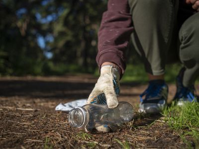 Woman collecting plastic garbage in forest