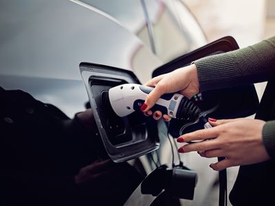 Woman is plugging/unplugging cable to electric car