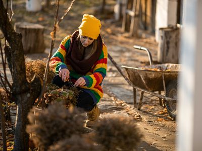 woman trims plants in fall