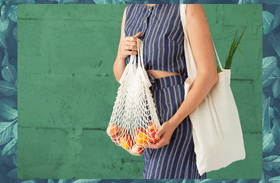 A shopper holding a net bag carrying fruit